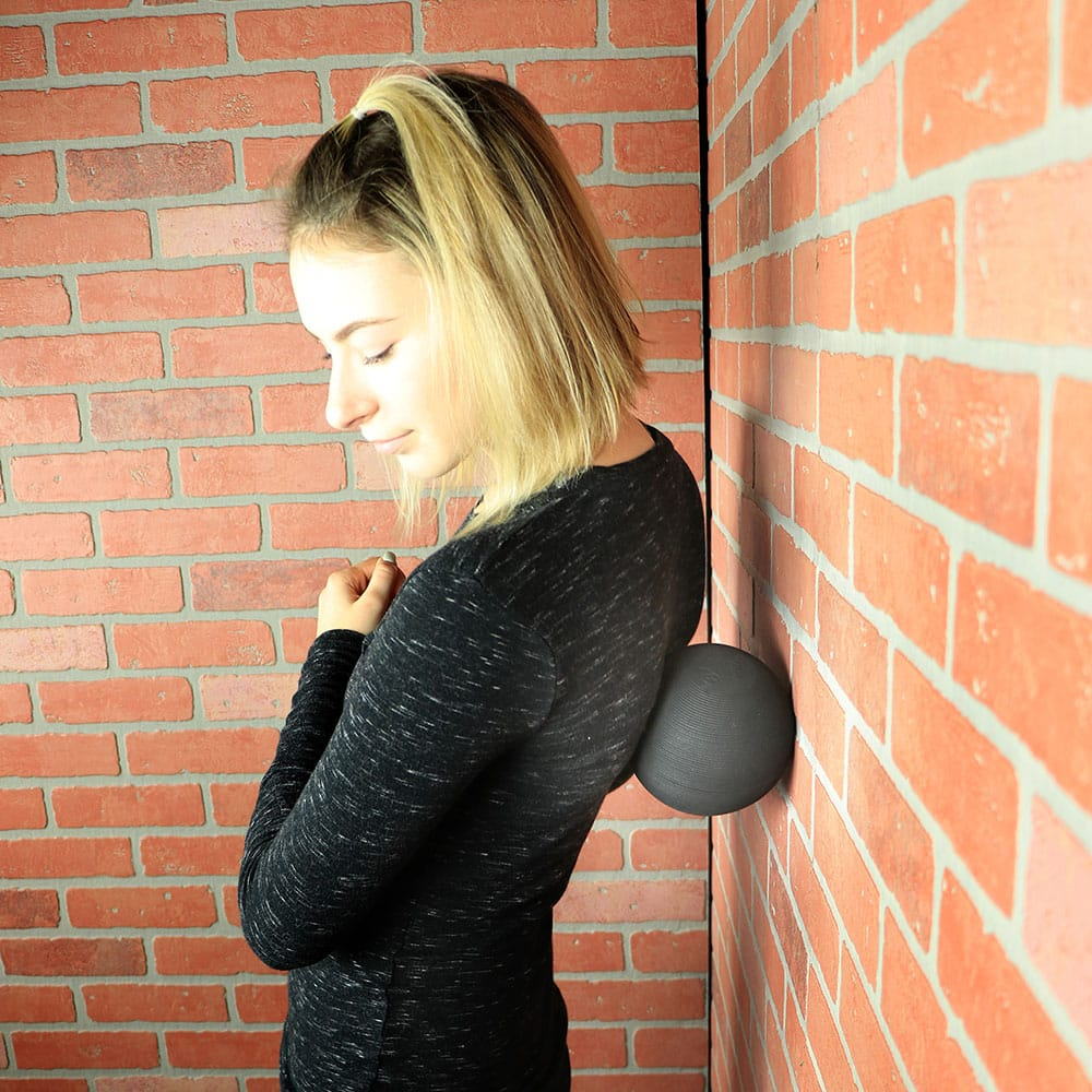 Tiger Tail Foam Roller Ball フォームローラーボール – 壁に当てて肩まわりをセルフケアしているシーン